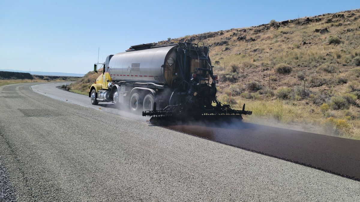 Distributor truck spraying a sealcoat over an asphalt surface